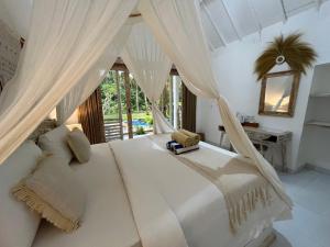 a bedroom with a white bed with curtains and a desk at Penida West palm cottage in Nusa Penida