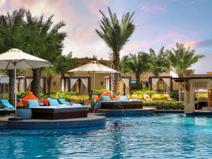 a resort swimming pool with chairs and umbrellas at Fairmont Ajman in Ajman 