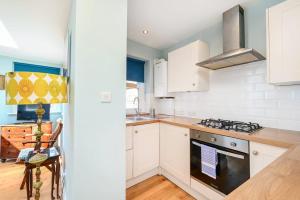 a kitchen with white cabinets and a stove top oven at Host & Stay - Blue Bolthole on Vicarage Lane in Rottingdean +10 photos