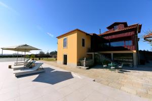 a yellow building with an umbrella and a patio at Ferienhaus Für 12 Personen In Esposende in Esposende
