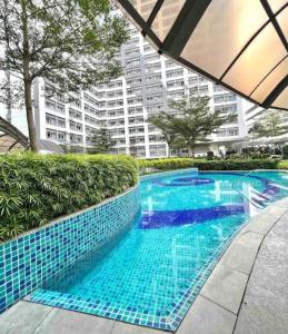 a blue tiled swimming pool in front of a building at Luxury for Less next to BGC and Makati CBD in Manila