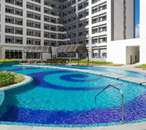a large pool with blue water in front of a building at Luxury for Less next to BGC and Makati CBD in Manila