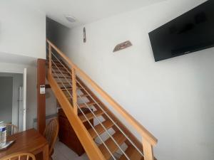 a wooden staircase with a flat screen tv on the wall at appartement dans un residence avec piscine - 3254 in Hourtin