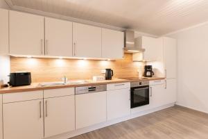 a kitchen with white cabinets and a sink at Ferienwohnung Lüttje Huus 35227 in Neuemoor