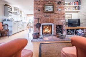 a living room with a brick fireplace with a tv at Fen Cottage, Walberswick in Walberswick