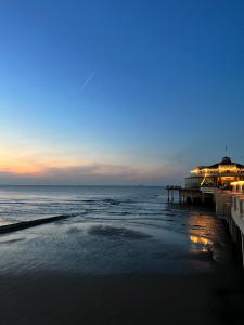 a beach with a pier and the ocean at dusk at Dune Du Clémot in Blankenberge
