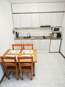 a kitchen with white cabinets and a wooden table and chairs at El Penell Apartament Xaloc in Vilamaniscle
