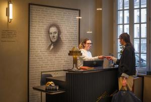 a woman is standing at a desk in a office at Hôtel Littéraire Stendhal et Spa in Nancy +109 photos