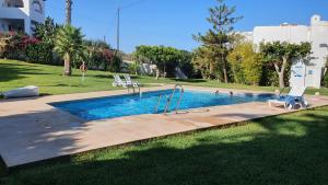 a swimming pool with two lounge chairs in a park at NEPTUNITO: Primera línea con Piscina in Mojácar