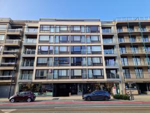 zwei Autos parkten vor einem großen Gebäude in der Unterkunft Premium Holidays - Studio Vriedom at the sea in Oostduinkerke