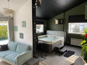 a living room with a tub and a couch at Le Refuge des Etoiles Gîte et Spa in Zutkerque
