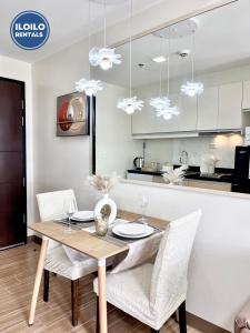 a dining room with a wooden table and white chairs at Room in Condo - Cozy, Modern and Homey, The Bliss Studio in Iloilo City