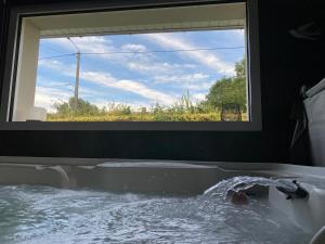 a bath tub with a window with water in it at Le Refuge des Etoiles Gîte et Spa in Zutkerque +12 photos