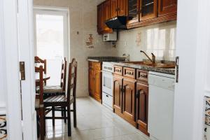 a kitchen with wooden cabinets and a sink and a table at Um pe na praia in Figueira da Foz