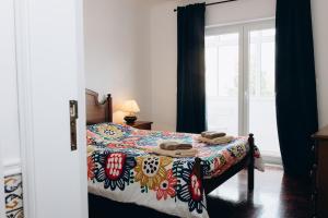 a bedroom with a bed with a colorful comforter at Um pe na praia in Figueira da Foz