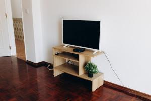a flat screen tv on a wooden stand in a room at Um pe na praia in Figueira da Foz