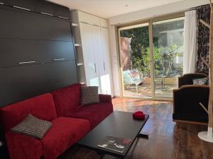 un soggiorno con un divano rosso e un tavolo di Studio tout confort au calme avec jardin proche Cannes a Le Cannet