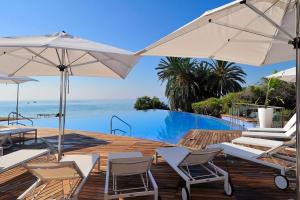 Una piscina con sillas y sombrillas y el océano. en Piso de lujo con piscina privada en las Colinas, en Orihuela Costa
