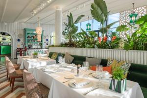 Un restaurante con mesas y sillas blancas y plantas. en Piso de lujo con piscina privada en las Colinas, en Orihuela Costa