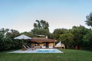 a pool with chairs and an umbrella and a house at Casa Nurru in Orosei