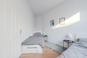 a white bedroom with two beds and two tables at Ferienwohnung Markranstädt - Geräumige Apartments nahe Leipzig in Markranstädt