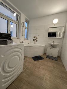 a white bathroom with a tub and a sink at Apartments in Nürnberg