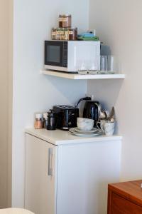 a microwave sitting on top of a white shelf at Serene Studio Escape on Madras in Christchurch