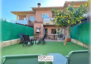 a patio with a tree and chairs and a house at DOMuum Holidays - CASA PUIGCERVER in Cambrils