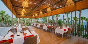ein Restaurant mit weißen Tischen, Stühlen und Palmen in der Unterkunft Delphin Deluxe Resort in Okurcalar
