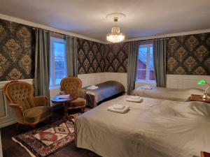a hotel room with two beds and two chairs at Svaneholm Hotel in Svanskog