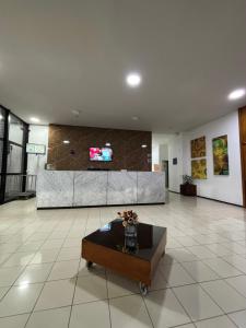 a lobby with a table and a tv on a wall at Studio moderno ALu lounge in São Luís