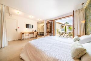 a bedroom with a large white bed and a desk at Les Capucines Saint Tropez in Saint-Tropez
