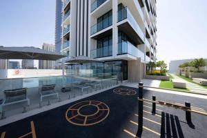 a building with a pool and some chairs and umbrellas at Elegant 1br Apt In Jvc With Spacious Balcony in Dubai