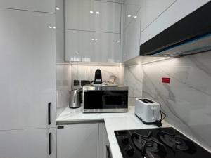 a kitchen with white cabinets and a microwave at Elegant 1br Apt In Jvc With Spacious Balcony in Dubai