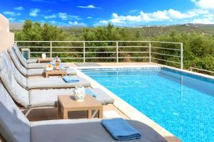 a pool with chaise lounge chairs and a swimming pool at Cretan Breeze Villa Beheizter Privater Swimmingpool in Dhrámia