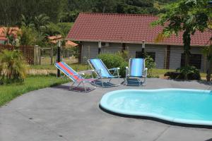 a group of chairs and a pool in a yard at casa de campo Chalé bela vista in Tijucas