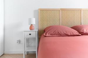 a bed with pink pillows and a lamp on a night stand at Joli T2 avec terrasse et Parking in Toulouse