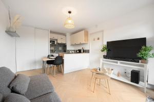 a living room with a gray couch and a kitchen at Joli T2 avec terrasse et Parking in Toulouse +13 photos