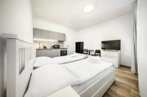 Una habitación blanca con dos camas y una cocina. en Residence Riverside, en Pec pod Sněžkou