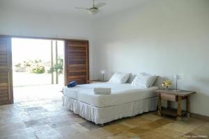 ein Schlafzimmer mit einem weißen Bett und einem großen Fenster in der Unterkunft Tudo Bom Kitesurf Dream Villa in Taíba
