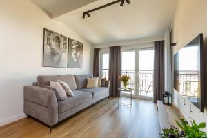 a living room with a couch and some windows at Apartamenty PREMIUM 56 obok Rynku Centrum, Parking - GARAŻ PODZIEMNY, wysoki standard, spokojna i cicha okolica, Parking - UNDERGROUND GARAGE, high standard, peaceful and quiet area in Kielce