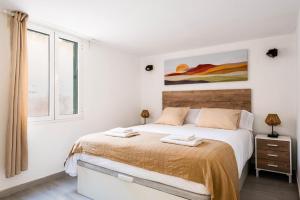 a white bedroom with a large bed and a window at Menorca Apartamento ALOHA by Mauter Villas in Cala en Blanes