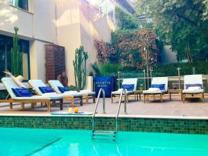a group of lounge chairs and a swimming pool at Croisette Beach Hotel Cannes - MGallery Collection in Cannes