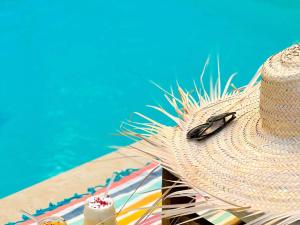 a straw hat and a drink next to a pool at Croisette Beach Hotel Cannes - MGallery Collection in Cannes