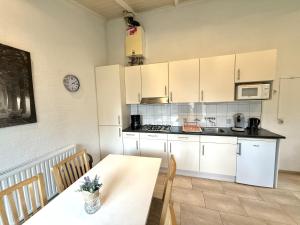 eine Küche mit weißen Schränken und einem Tisch mit Stühlen in der Unterkunft Bungalowpark Simpelveld - Schakel 6 in Simpelveld + 6 Fotos
