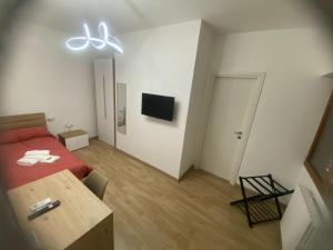 a room with a bed and a table and a television at Le Ninfe Guest House in Cisterna di Latina