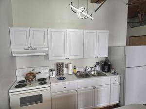 a kitchen with white cabinets and a stove and a sink at Detwah Downtown Studio Loft in Detroit