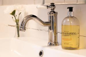 a bathroom sink with a soap bottle next to a faucet at Grund Cabin in Hvolsvöllur +21 photos