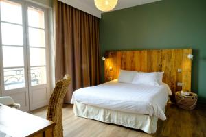a bedroom with a large bed with a wooden headboard at Hôtel & Restaurant Le Moulin de Moissac in Moissac +7 photos