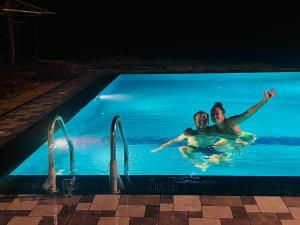 two people swimming in a swimming pool at night at Dhanaya Safari Home in Udawalawe